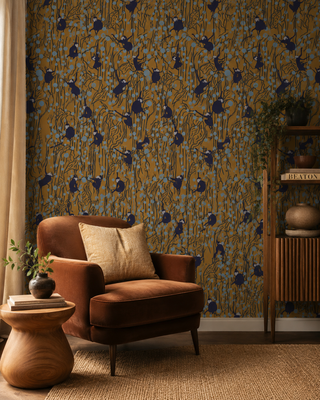 Papier peint Monkey Garden avec silhouettes de singes, feuillages graphiques, touches bleu ciel et fond ocre dans un style décoratif contemporain.