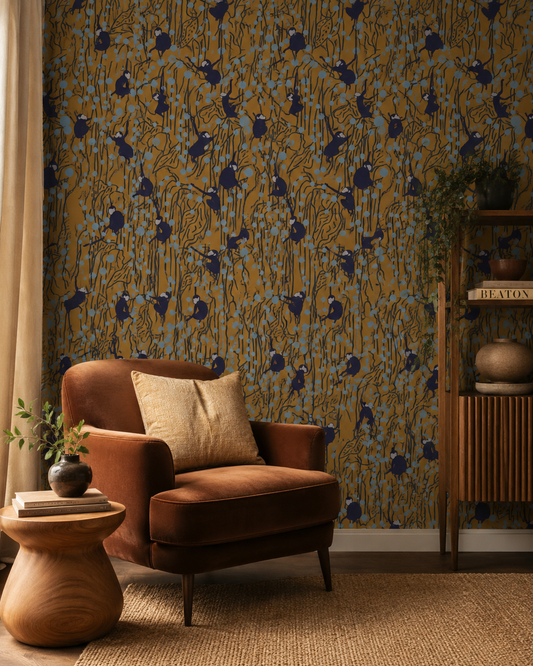 Papier peint Monkey Garden avec silhouettes de singes, feuillages graphiques, touches bleu ciel et fond ocre dans un style décoratif contemporain.