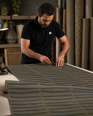 Papier peint Sand Lines avec motif de lignes organiques foncées sur fond taupe dans un intérieur contemporain.